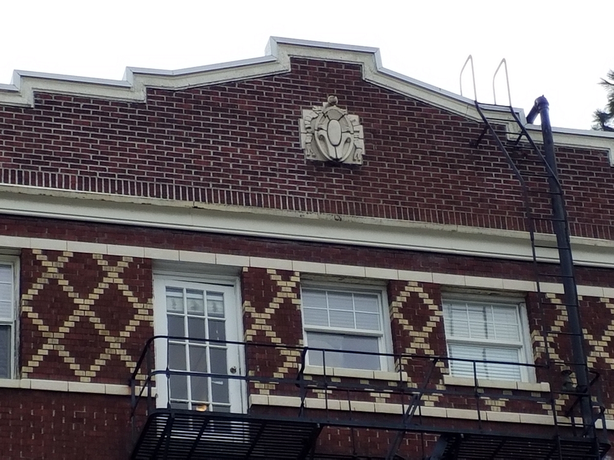 Photo taken Feb. 2018. South end upper detail cartouche. The Empress Apartments Hotel.  Built in 1926 at 16th and Washington.  Current Address in 2017 is 1539-1541 W Burnside. Order #165 Glaze #22M in Leonard Martins order book for Columbia Terra Cotta Co.  The name of the hotel was for a period of time "Marquette Manor"